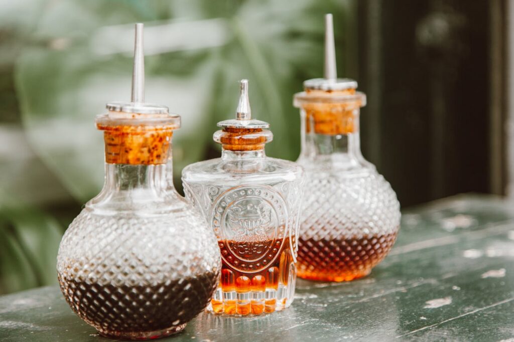 Close-up of three vintage glass condiment bottles with spices on a rustic table.
